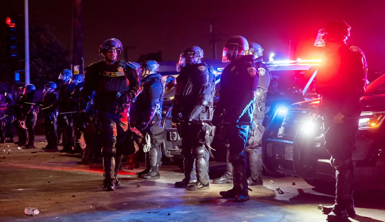 Petugas penegak hukum berjaga-jaga ketika mereka berhadapan dengan para demonstran saat aksi protes menyusul operasi imigrasi federal, di lingkungan Compton, Los Angeles, California pada tanggal 8 Juni 2025. (ETIENNE LAURENT/AFP)