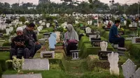 Keluarga berziarah ke makam kerabat yang telah meninggal di Surabaya, Indonesia, sebagai bagian dari nyekar, tradisi yang dilakukan sebelum Ramadan. (AFP/Arsip)
